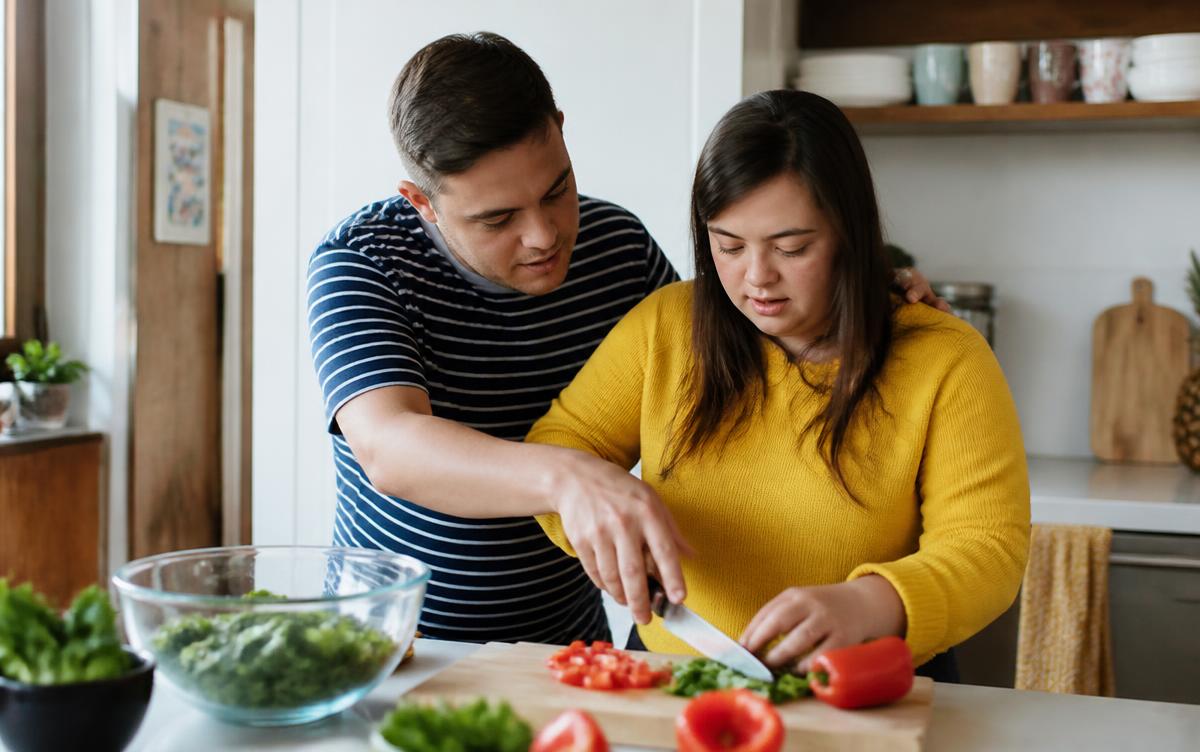 Two adults preparing a meal together at a kitchen counter with respectful guidance